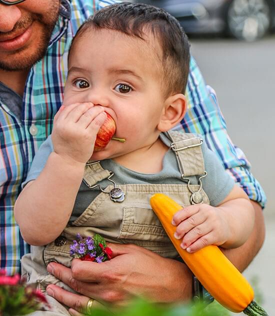 Baby stuffing his face with fruit